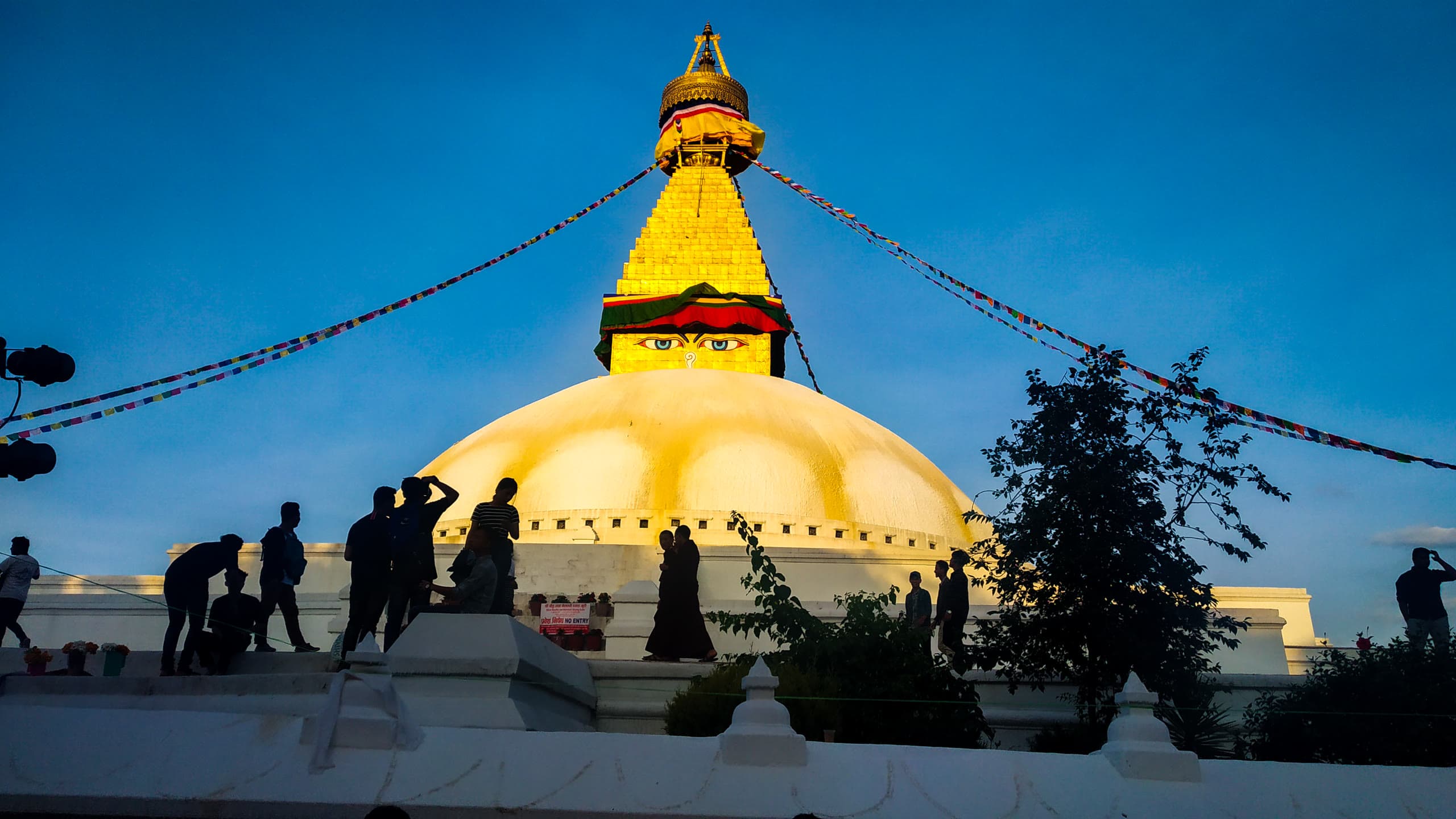 Devotees circumambulating the whitewashed dome of Boudhanath Stupa at twilight